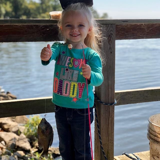 little girl holding up the fish she caught