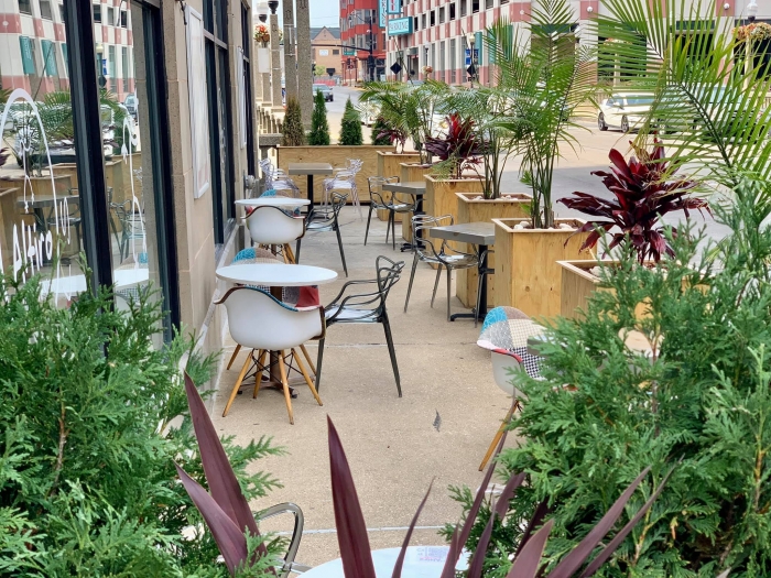 outdoor sidewalk cafe surrounded by tall fern and palm plants