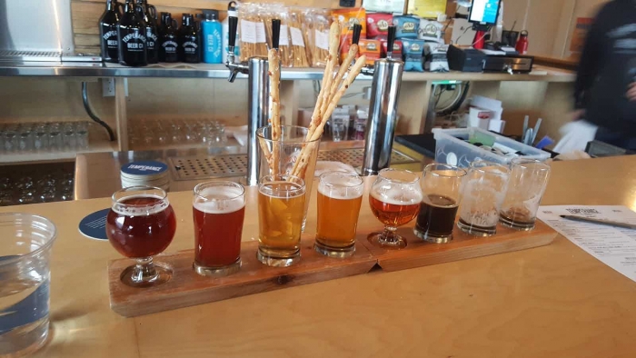 flight of 8 beers in short glasses, two are empty