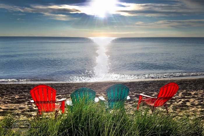 colorful Adarondak chairs sitting on beach looking at sunrise on the lake