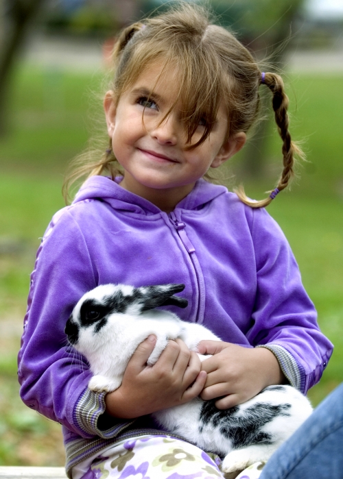 young girl smiling at camara holding a bunny