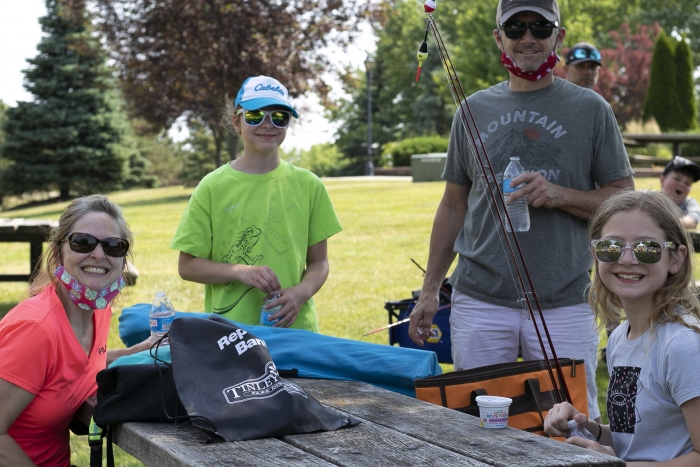 mom, dad, boy, girl at a picnic table drinking bottles of water with fishing poles