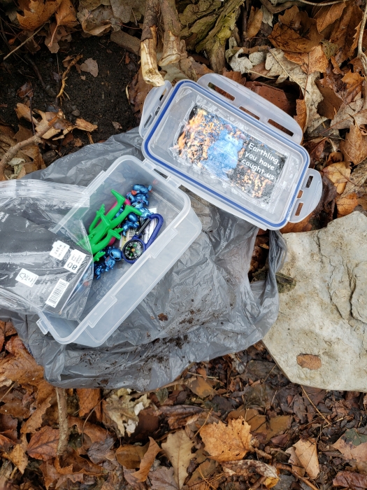 open geocache container on ground covered in leaves