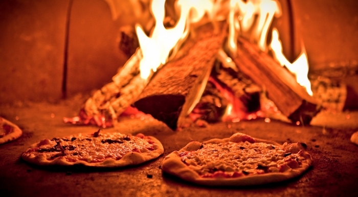 looking inside woodfired pizza oven with 2 pizzas cooking