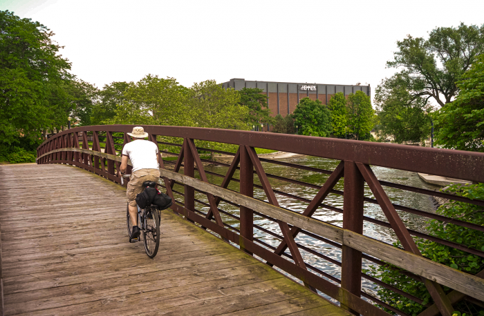 man riding bicycle on wooden bridge over a small river