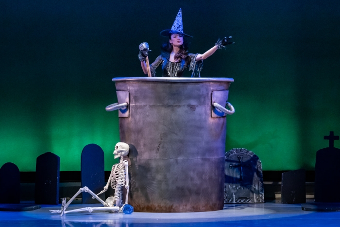dancer in witch's costume stirring a giant cauldron