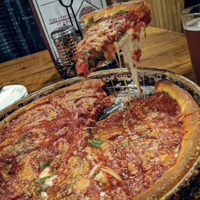 slick of thick crust pizza with gooey cheese being lifted out from the pizza