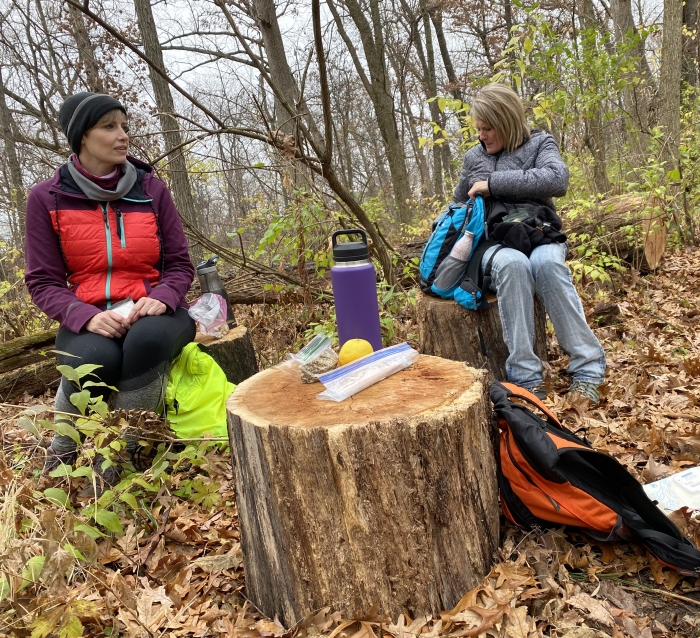 two women hikers enjoying lunch in forest in the fall