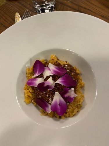 White bowl of yellow rice with orchid petals topping rice