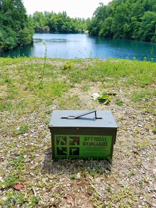 geocache container sitting by lake with trees in background