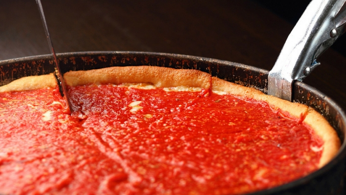 deepdish pizza in pan covered in tomato sauce