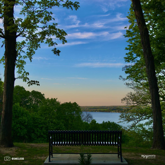 metal park bench on hilltop overlooking water