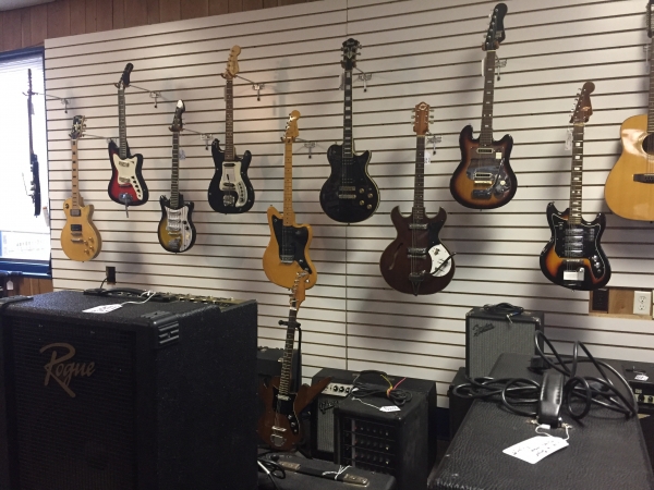 Wall of guitars sold at store.