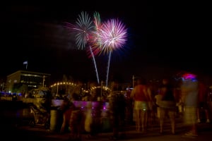 Fireworks over the bridge with people standing around watching.
