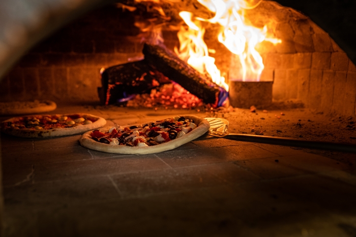 brick woodfired pizza oven with 3 pizzas cooking