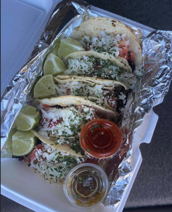5 soft flour shell beef tacos in a to-go container with limes and salsa on the side