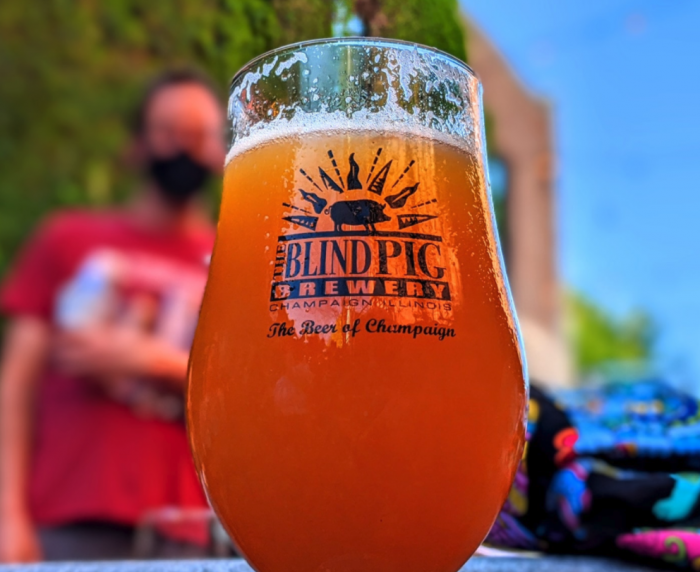 close-up of amber glass of beer with blurry man in the background