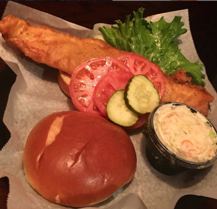 long battered fish fillet on bun with lettuce and tomato and coleslaw in separate plastic container