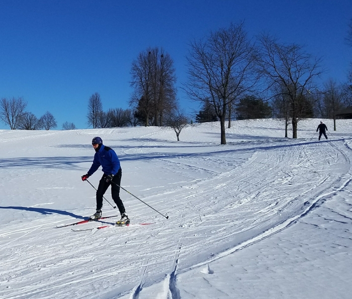 2 men cross country skiing on sunny clear day on groomed snow trail