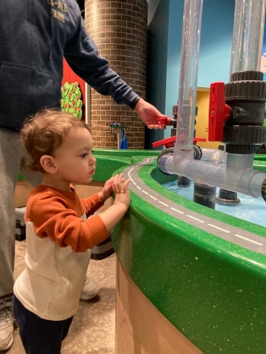 toddler boy looking at museum toy