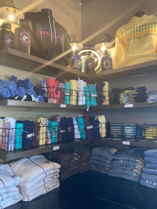 corner with merchandise displayed with shirts, hats, and growlers
