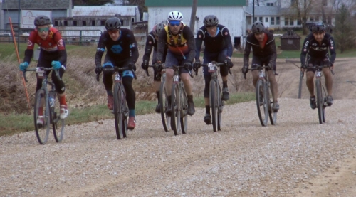 six men bicycle racing on gravel road