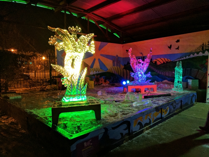 3 ice sculptures lit with colored lights at night